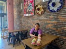 Woman in ice cream shop at table with 4 scoops of ice cream on carry out server